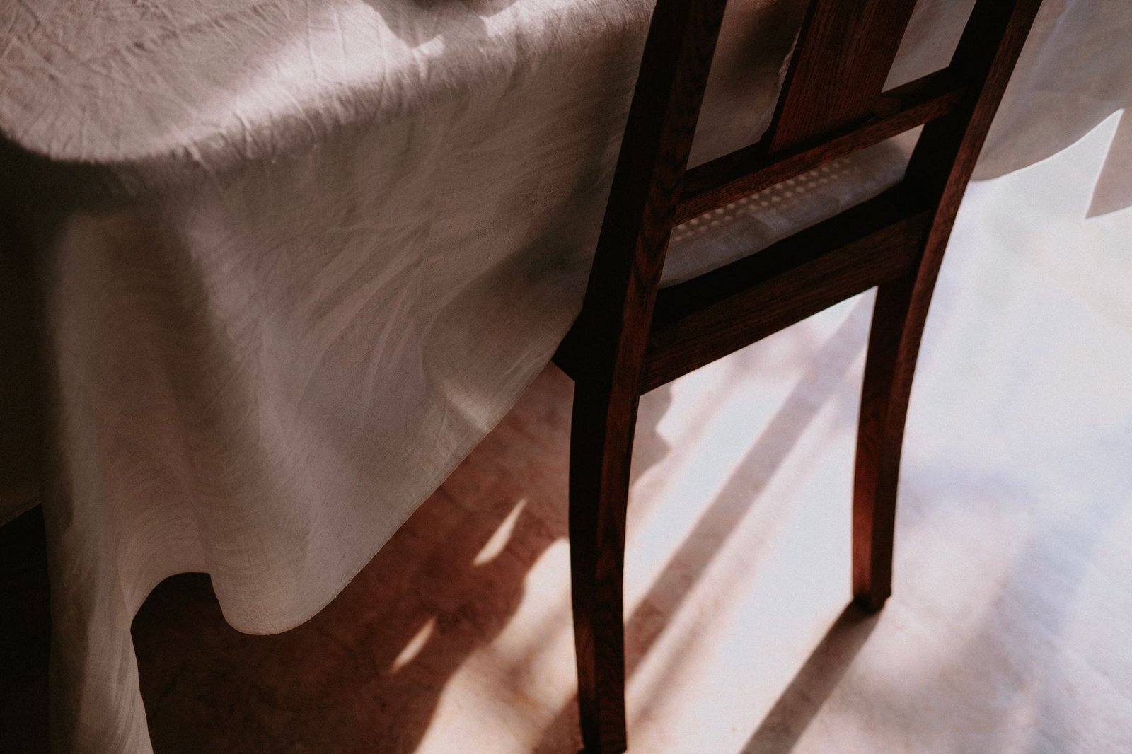 A linen-covered table and an empty wooden chair in soft morning light.