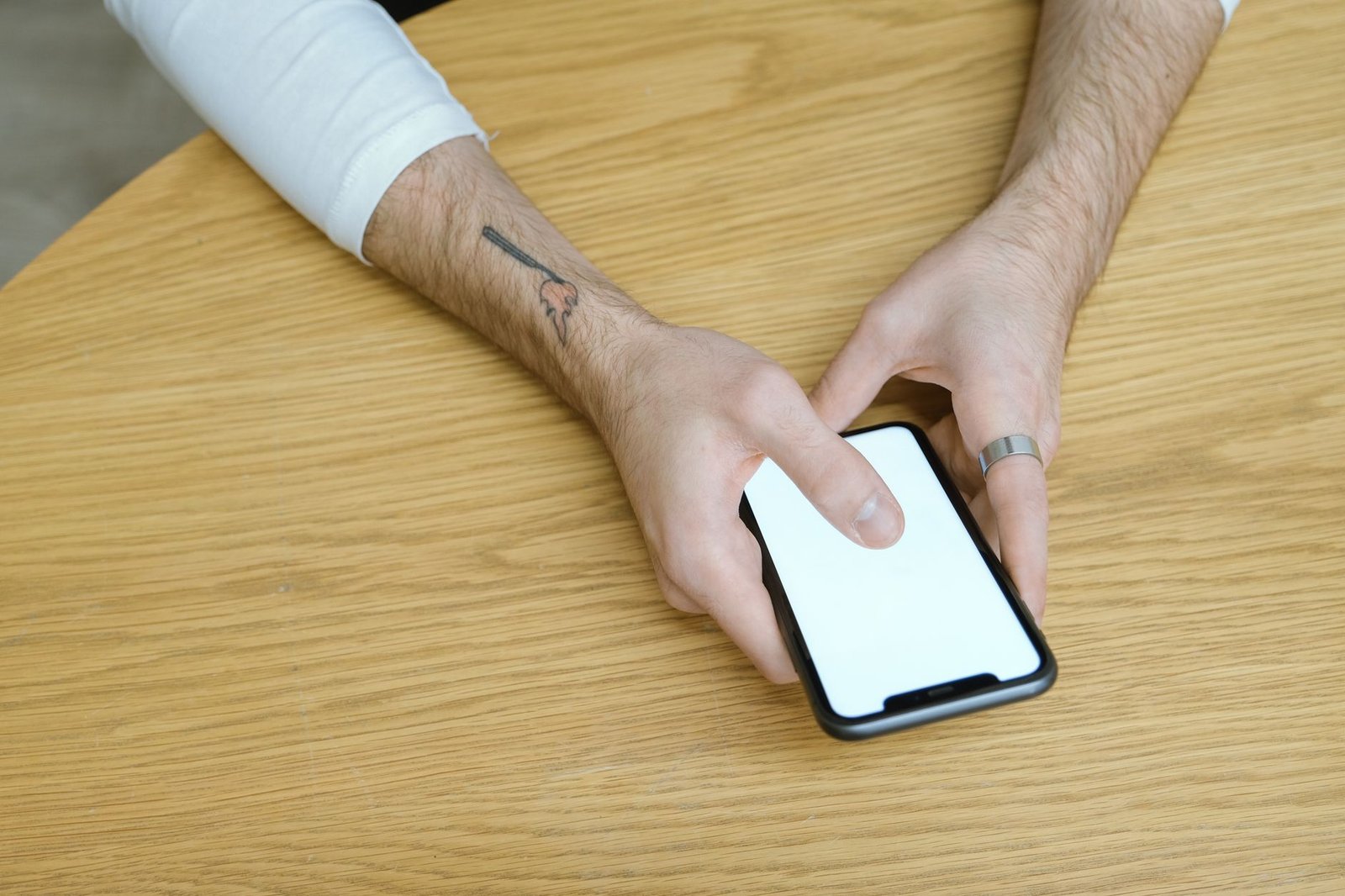A phone resting on a wooden table, held in both hands.